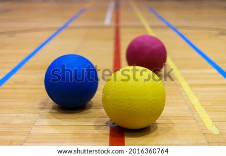 Three dodge balls on the hardwood floor in a gymnasium indoor