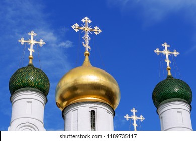 Three domes with crosses (one golden and two green) of the Orthodox Church, blue sky.