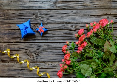 Three Dozen Pink Roses On Stems With Leaves By Coiled Yellow Ribbon And A Couple Of Small Blue Presents