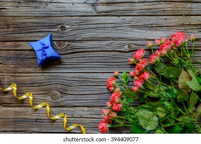 Three Dozen Pink Roses On Stems With Leaves By Coiled Yellow Ribbon And A Couple Of Small Blue Presents