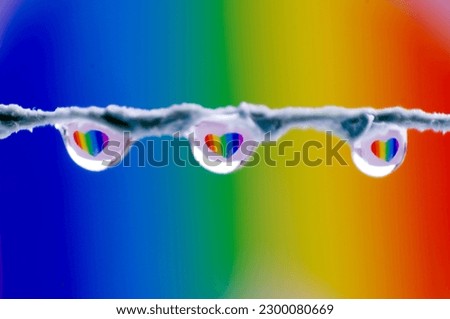 Three drops hanging from a string on a background with rainbow colors with hearts reflected inside. LGTB concept