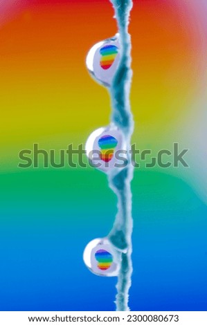 Three drops hanging from a string on a background with rainbow colors with hearts reflected inside. Vertical. LGTB Concept