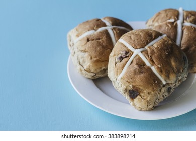 Three Easter Hot Cross Buns On A White Plate On A Blue Background