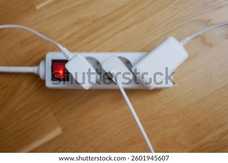 Three electric cables are plugged into a power strip socket extension cord