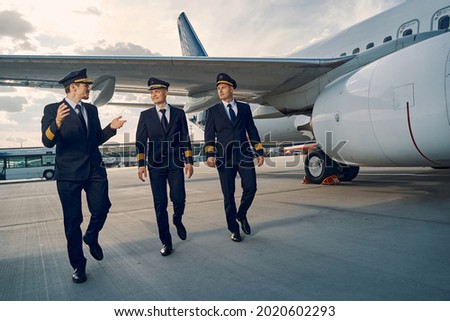 Three elegant aviators going along the runway