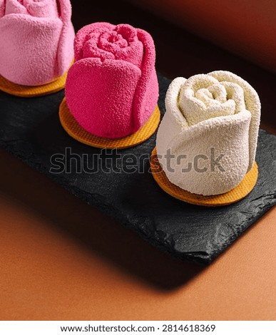 Three elegant rose shaped mousse desserts displaying pink, fuchsia, and white colors