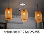 Three elegant woven pendant lights suspended from the ceiling, casting a warm glow in a modern interior setting, creating a cozy and inviting atmosphere.