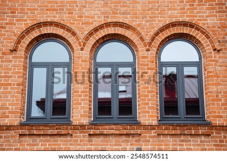 Three elegantly arched windows on the exterior of a visually striking red brick building significantly enhance its architectural appeal while contributing to its overall charming and inviting facade