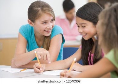 Three Elementary School Pupils Talking In Classroom