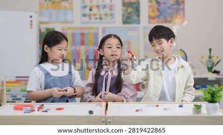Three elementary students explore magnetic attraction and repulsion using horseshoe magnets and colorful blocks.