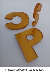 Three Embossed Metallic Gold Letters From Acrylic Pieces Isolated On A White Background