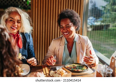 Three empowered business women at the cafe restaurant discussing during lunch break