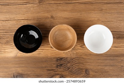 Three empty bowls on table, white porcelain, black and wooden dishes on tabletop, rustic dish mockup, eco bio kitchen desktop banner with copy space for text top view