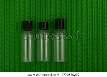 Three empty cosmetic containers placed on a green suitcase, the permitted capacity of containers in hand luggage, and a change in the capacity of bottles that can be carried on board an aircraft.