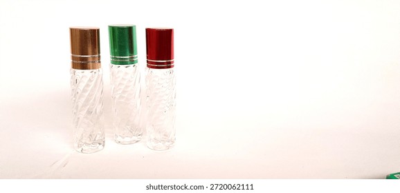 Three empty swirl-patterned glass roll-on bottles with gold, green, and red metallic caps isolated on white background.