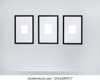 Three empty vertical picture frames hanging on white wall, Wall art mockup set of 3 posters, blank space frame modern interior style, minimalist with clipping path