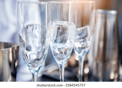 Three empty wine glasses with a large ice cube, preparations for the celebration, wine and champagne tasting, blurred background, selective focus. Preparing a coctail party event.