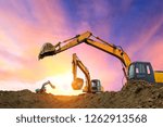 Three excavators work on construction site at sunset
