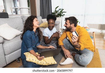 Three Excited Friends Buying A Vacation Tickets Trip Online With A Credit Card And A Laptop Sitting On A Floor In The Living Room At Home. Group Of People Online Shopping With Computer.