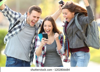 Three excited students checking exam grades online in a smart phone