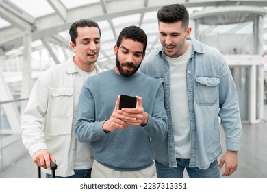 Three Excited Tourists Men Using Cellphone Booking Travel Tickets Online In Mobile Application Standing In Modern Airport Terminal Indoors. Technology And Transportation Concept - Shutterstock ID 2287313351