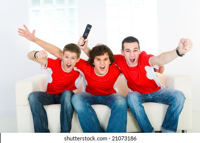 Three Exciting Men Sitting On Couch And Watching Sport On TV.