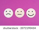 Three faces, smiling, sad in different colors on a pink background, copy space, rating, communication, customer feedback