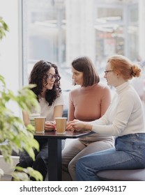 three female colleagues or students are working on a laptop and discussing a project or creative term paper. three female friends in coworking work online in an intranet or video chat for negotiations - Shutterstock ID 2169943117