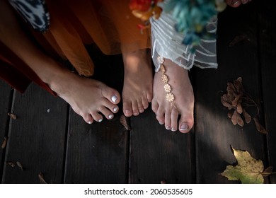 Three Female Feet Together On Wood With Leaves Painted Nails Barefoot Formal Dress Bottoms