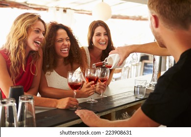 Three Female Friends Enjoying Drink At Outdoor Bar