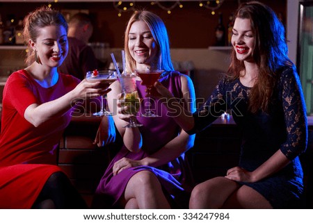 Three female friends enjoying drinking in the club
