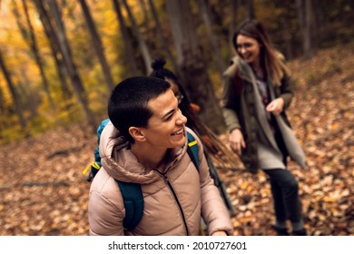 Three female friends enjoying hiking in forest on a beautiful autumn day.