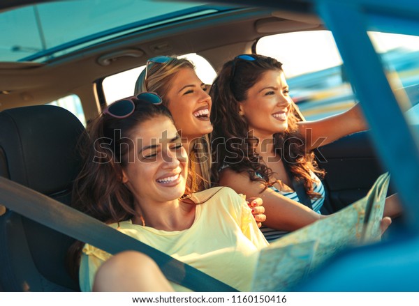 Three\
female friends enjoying traveling in the\
car.