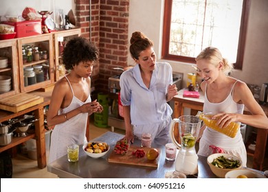 Three Female Friends Making Smoothies In Kitchen