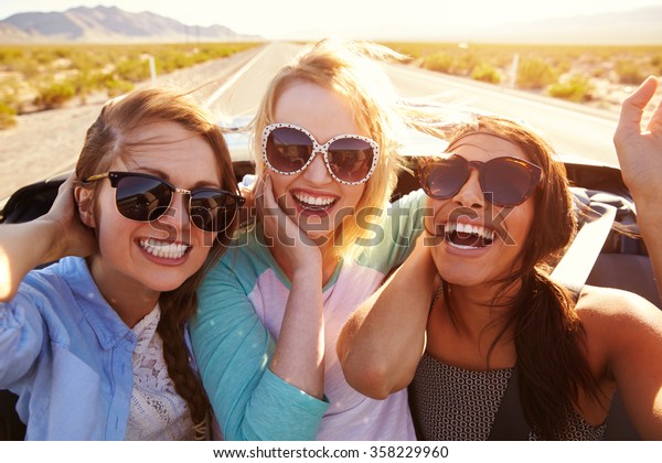 Three Female Friends On Road Trip In Back Of\
Convertible Car