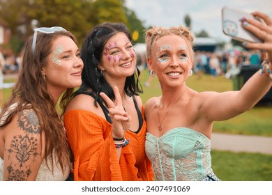 Three Female Friends Wearing Glitter Posing For Selfie At Summer Music Festival - Powered by Shutterstock