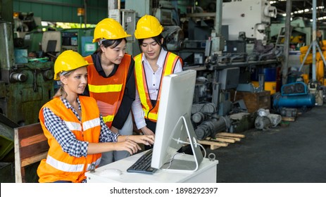 Three female mechanical engineers or factory workers in safety uniform work with computer to check the factory operation in a warehouse