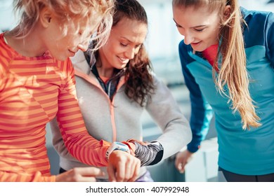 Three female runners checking time on smartwatches