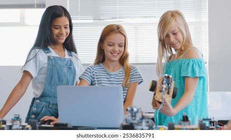 Three Female Students Building And Programming Robot Vehicle In After School Computer Coding Class