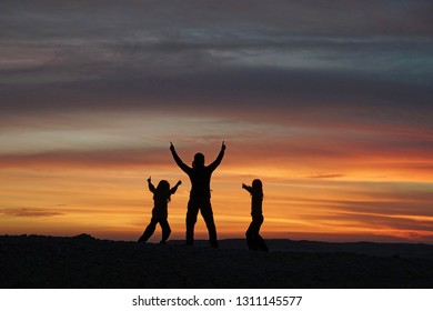 Three Figures in silhouette dancing at sunset (natural silhouette in-camera, not added post-production)