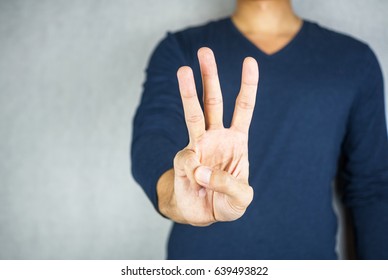 three finger salute hand gesture, on light grey background