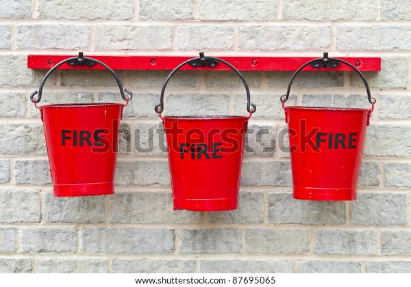 Three fire buckets hanging\
on a wall