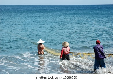 Three fisherman work together to pull in their net. Lombok, Indonesia