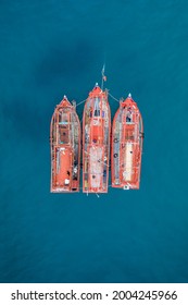 Three fishing boats together with shallow coral reef below, drone aerial ariel uav view orange boat blue water color contrast no people and copy space