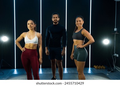 Three fit trainers posing in a gym before starting a fitness session - Powered by Shutterstock