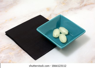 Three Fizzy Lemon Hard Candies In Blue Candy Dish With Black Napkins On Table