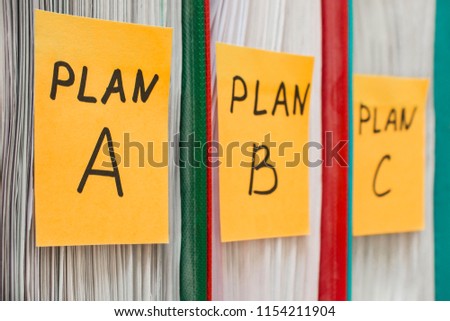 Three folders with stickers, on which plan a, b or c is written. Business planning. A spare option. Difficulties of enterprise management. Decision making, development options. Background in blur.