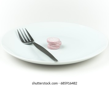 Three Food Supplement Tablets And Fork On A White Plate