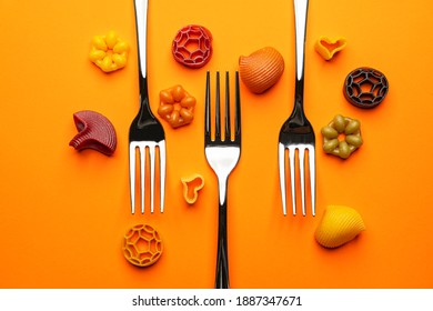 three forks with some types of colored pasta on an orange surface - Shutterstock ID 1887347671