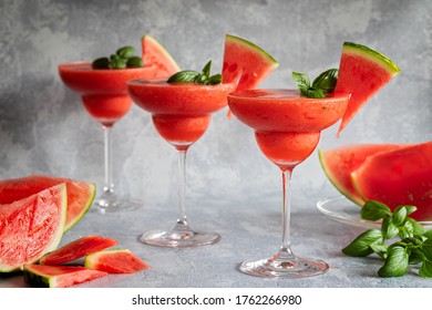 Three Fresh Frozen Blended Margarita Drinks With Strawberries And Watermelon. The Drinks Are Garnished With Basil Leaves And Watermelon. Gray Background. Horizontal With Copy Space Room For Text.